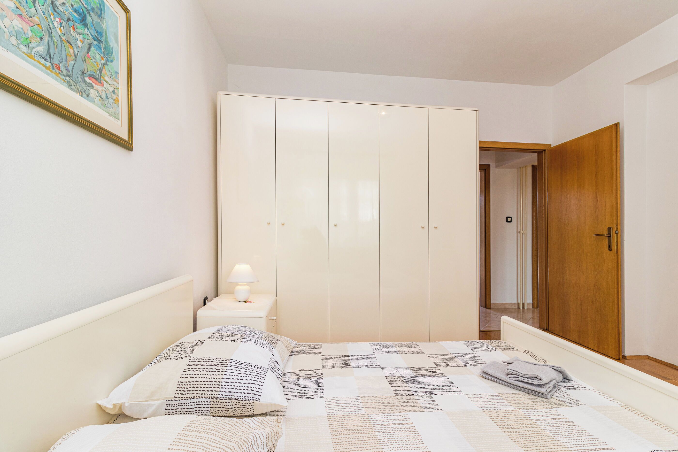 Une chambre à coucher comprenant un lit, une table de chevet, une armoire et une porte donnant sur une autre pièce.
