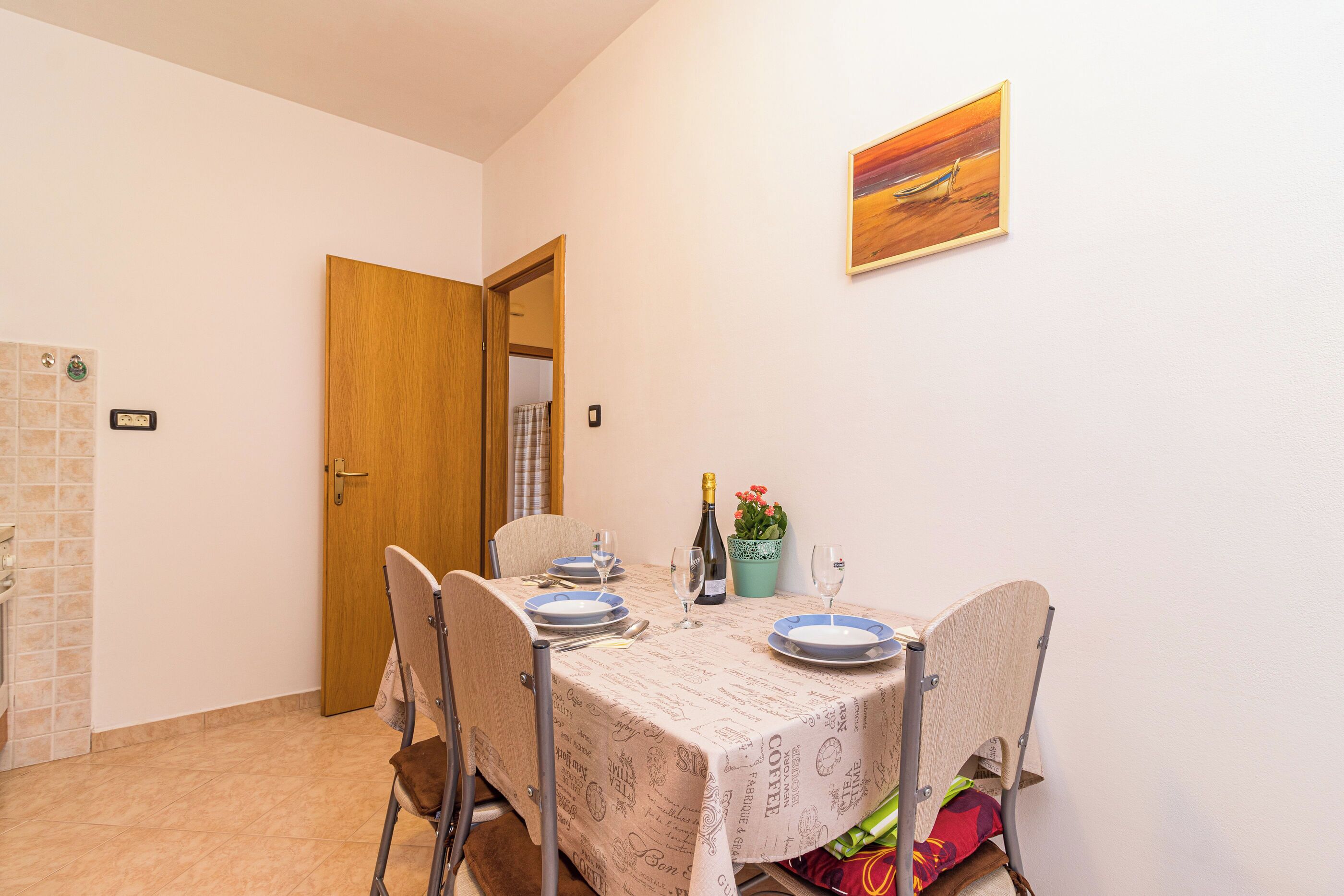 A dining area with a table set for four, a bottle of wine, and a potted plant.