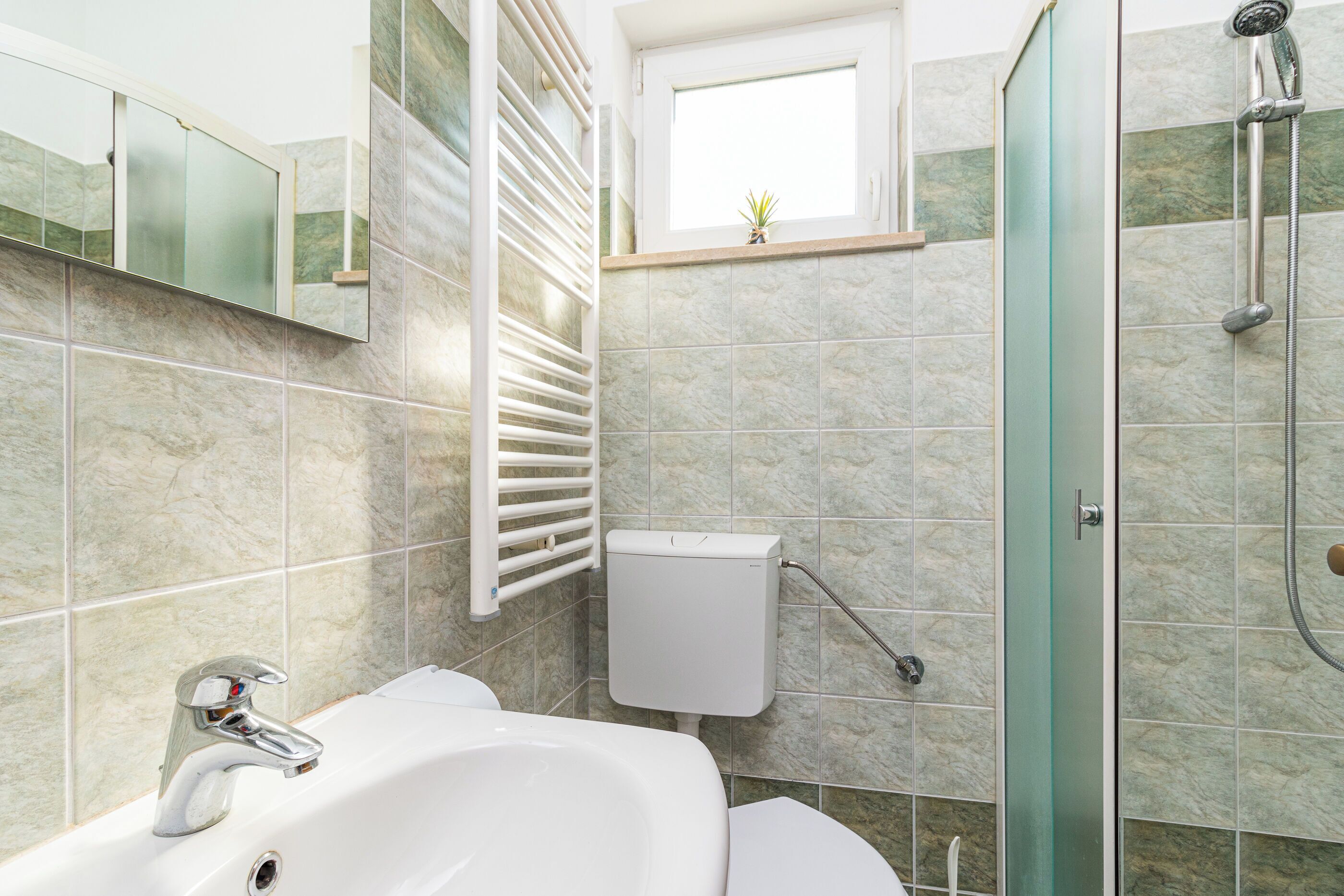 A bathroom with a white sink, a glass shower enclosure, and a toilet.