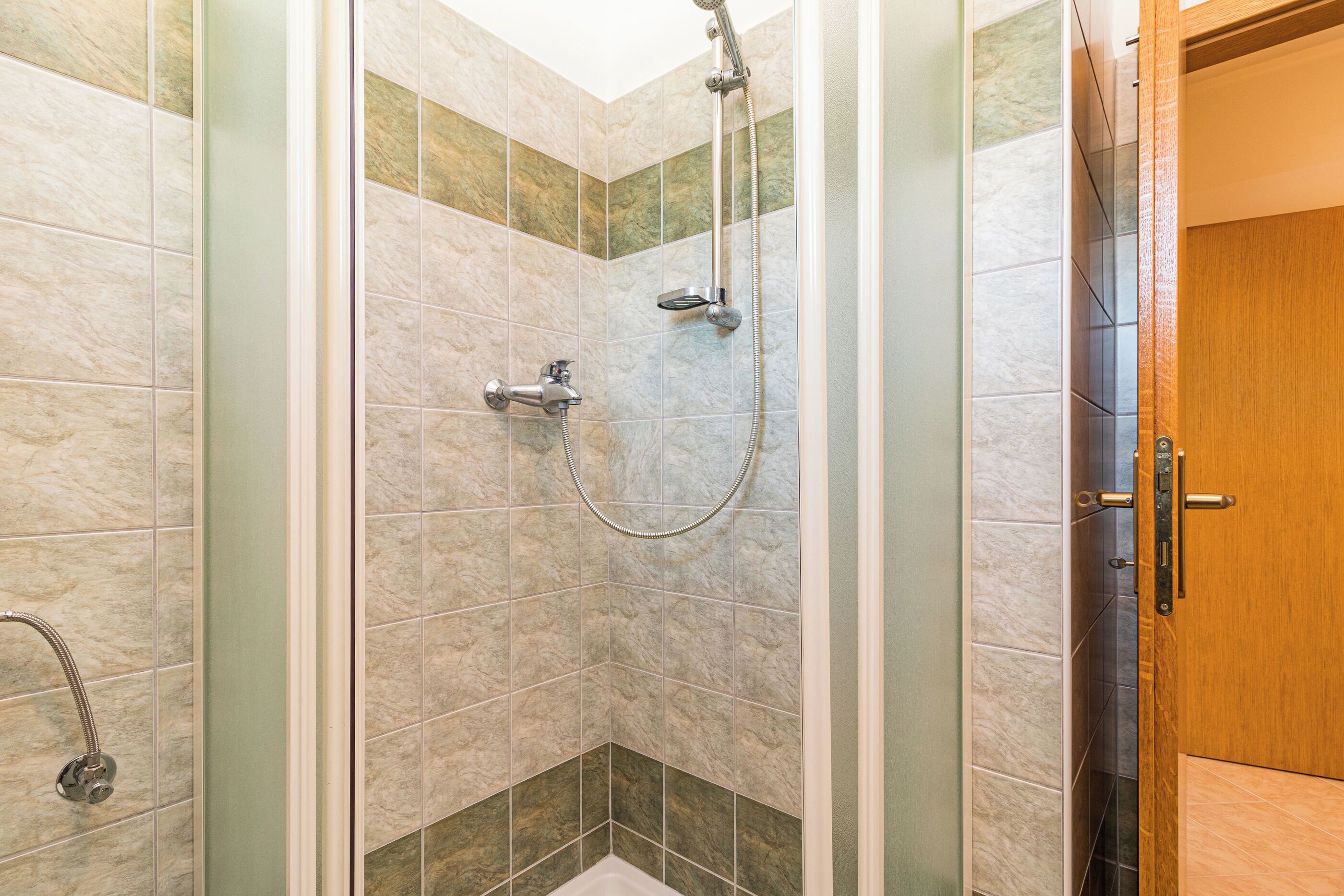 Eine Dusche mit Handbrause und Armaturen am Wand.