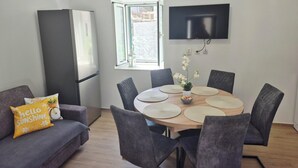 A modern living room with a dining area, grey sofas, a flat-screen TV, and a window with a view. - House Mateljan (Jelsa)
