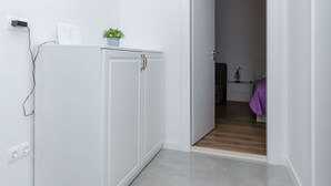 A minimalist room with a white wardrobe, a small potted plant, and a door leading to another room with a purple bedspread. - House Mateljan (Jelsa)