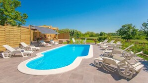 Piscina com espreguiçadeiras e cerca de madeira.