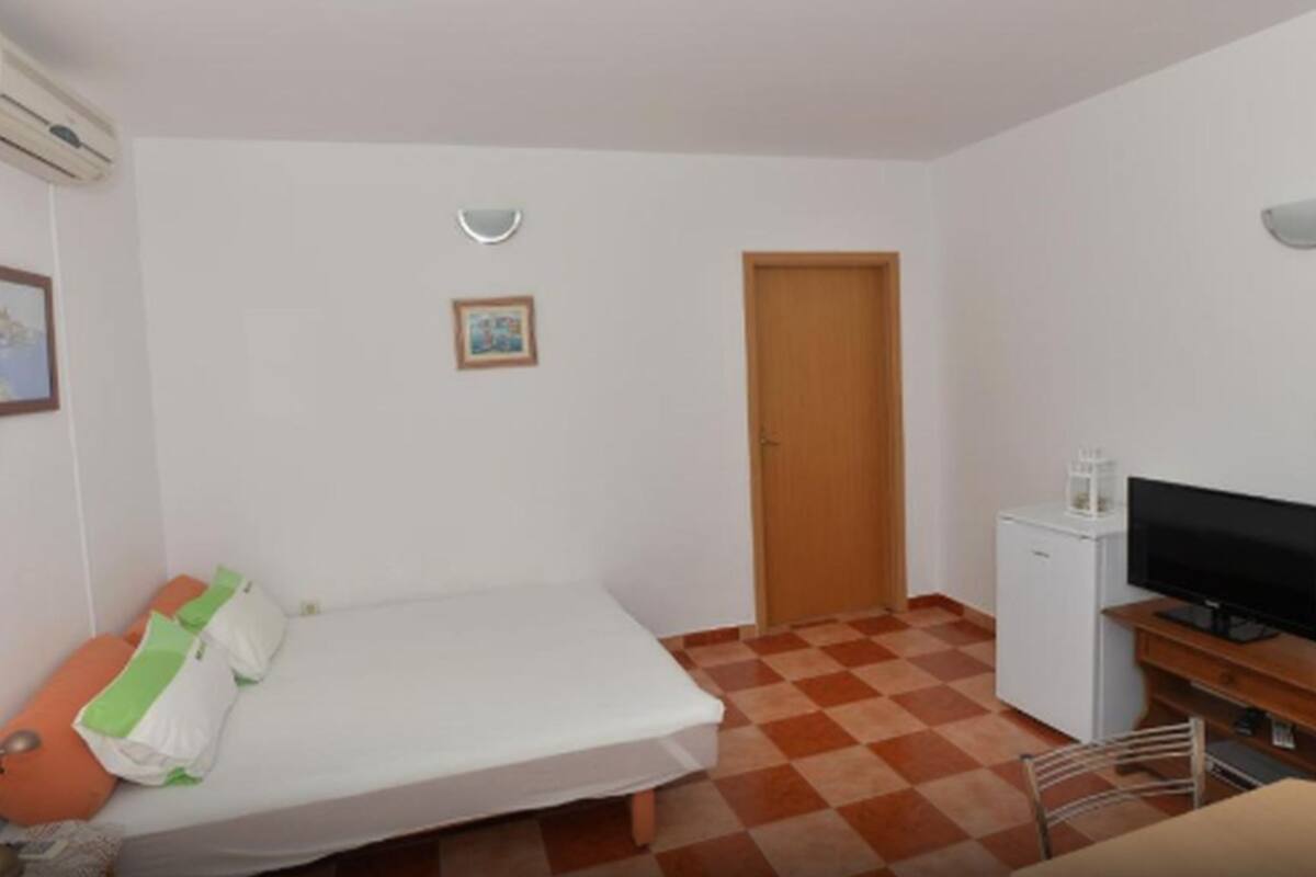Une petite chambre propre, équipée d’un lit, d’une télévision et d’un réfrigérateur.