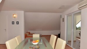 A dining area with a glass table, four chairs, and a fruit bowl. - Apartments Kovami (Podgora)