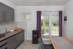 Et moderne køkken med indbygget komfur, et spiseområde med bænk og en balkon med udsigt.