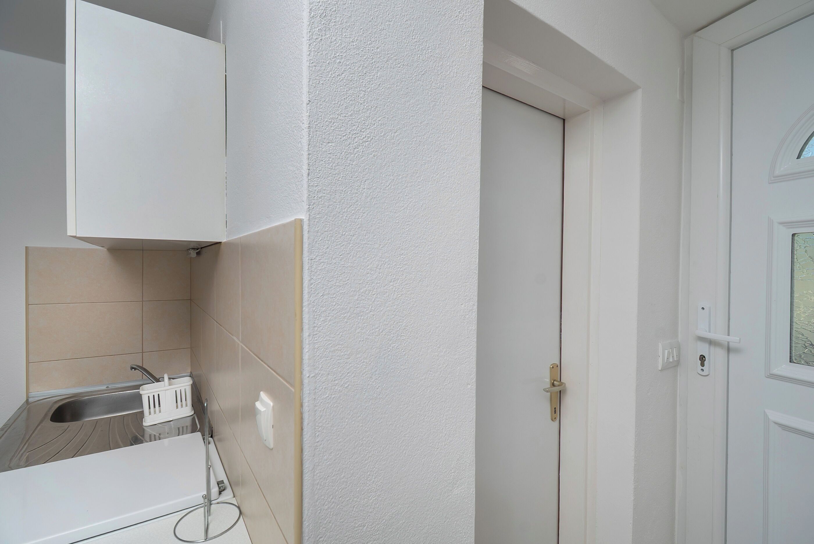 Eine Küche mit Spüle, einem weißen Schrank und einer Tür.