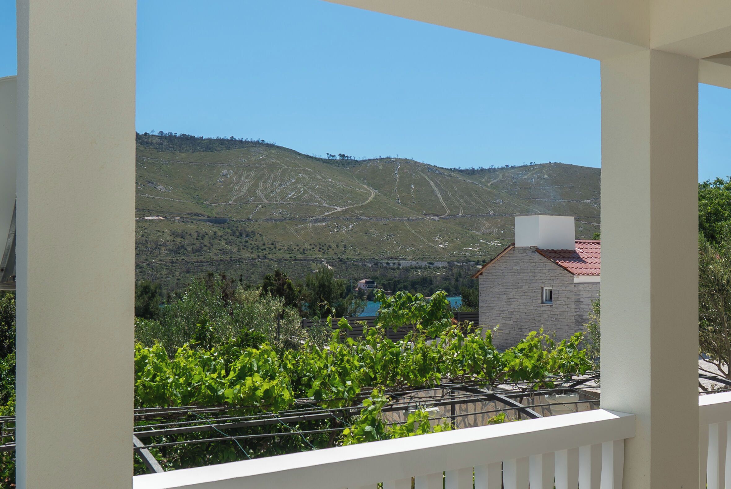 A balcony with a view of a vineyard and a stone building in the distance.