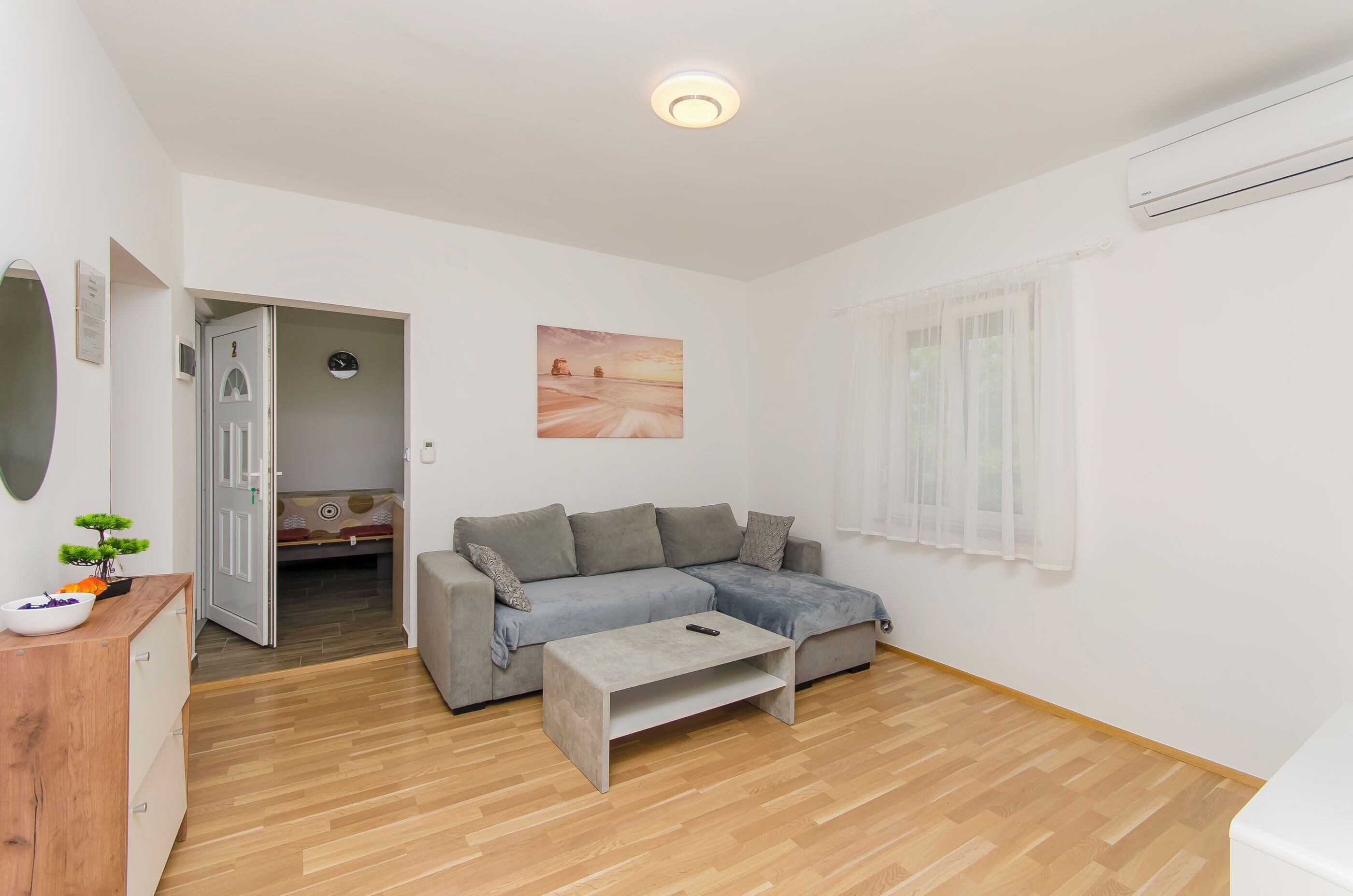 Una sala de estar moderna con un sofá gris, una mesa de centro de madera y un cuadro en la pared.