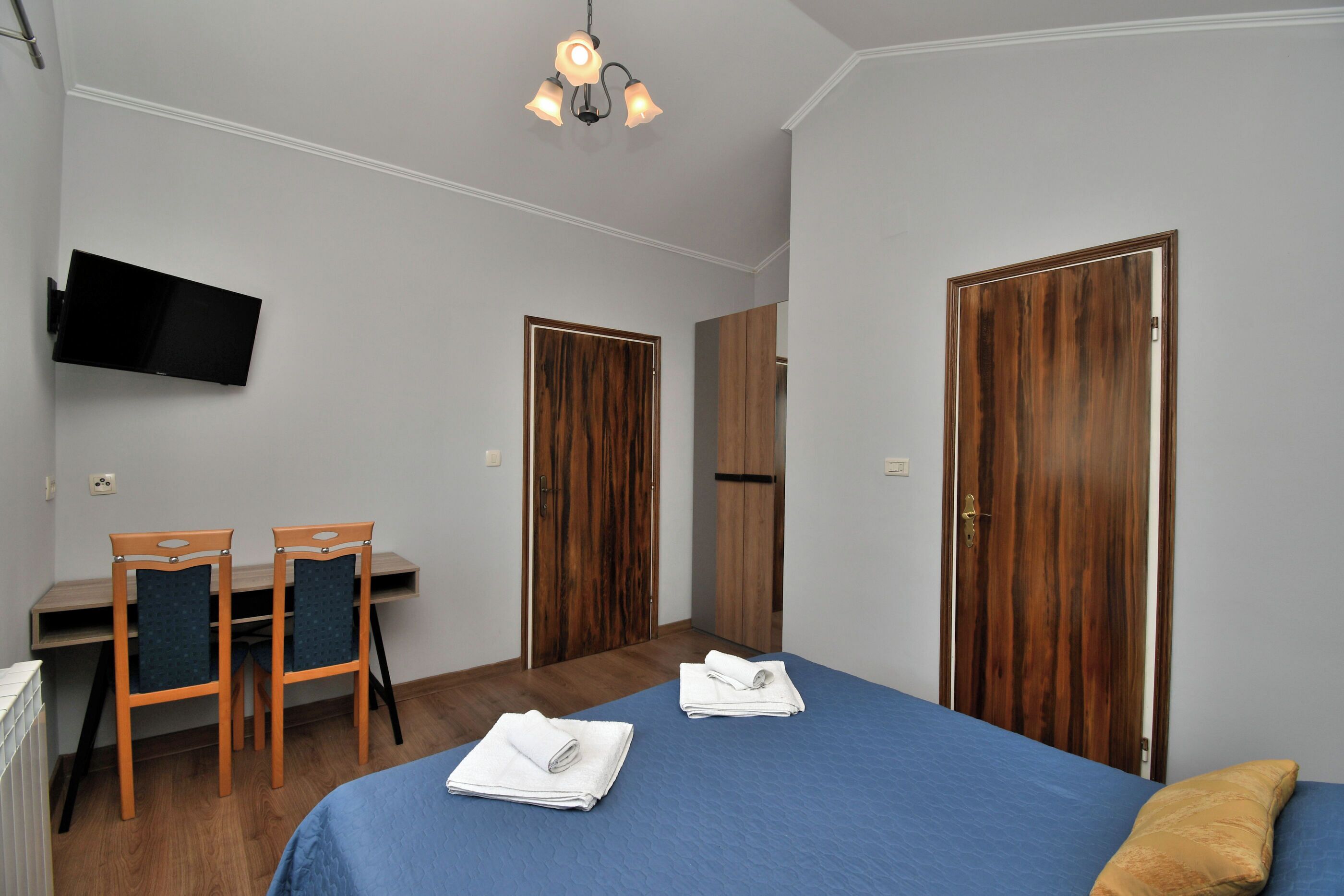 Une chambre à coucher comprenant un lit, deux chaises, un bureau, une télévision et deux armoires.