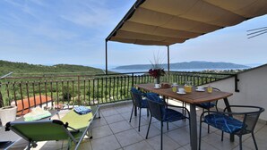 Un balcone con tavolo, sedie e vista sul mare.