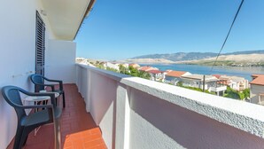 A balcony with two chairs and a small table, overlooking a body of water and a coastal town. - Apartments Bepo i Marija Pag (Pag)