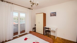A bedroom with a bed, a desk, a wardrobe, and a view of the outdoors. - Apartments Bepo i Marija Pag (Pag)