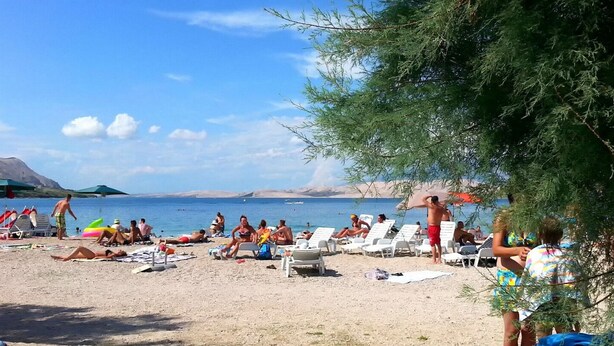 A beach with sun loungers and umbrellas, a clear sky, and a calm sea. - Apartments Bepo i Marija Pag (Pag)