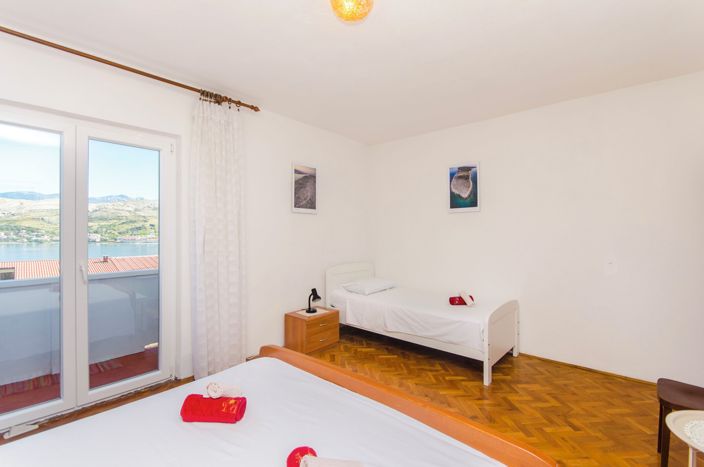 Quarto de hotel com uma cama, mesa de cabeceira, pequena mesa e vista para o exterior.