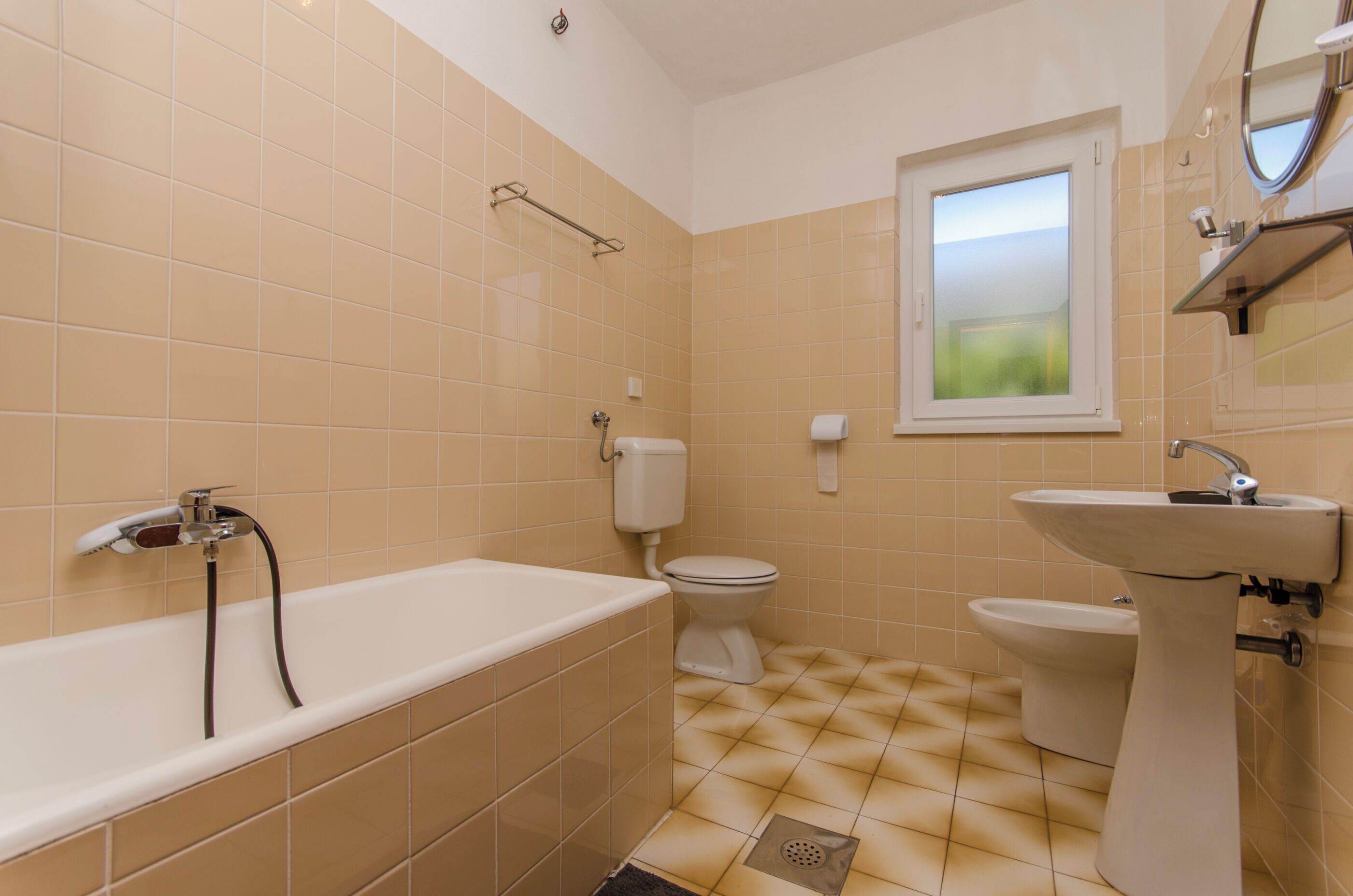 Une salle de bain équipée d’une baignoire, de toilettes, d’un bidet et d’un lavabo.