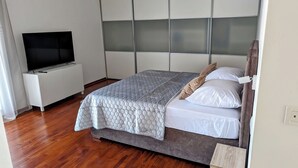 A bedroom with a bed, a TV, and a wooden floor. - Apartment Penthouse (Split)