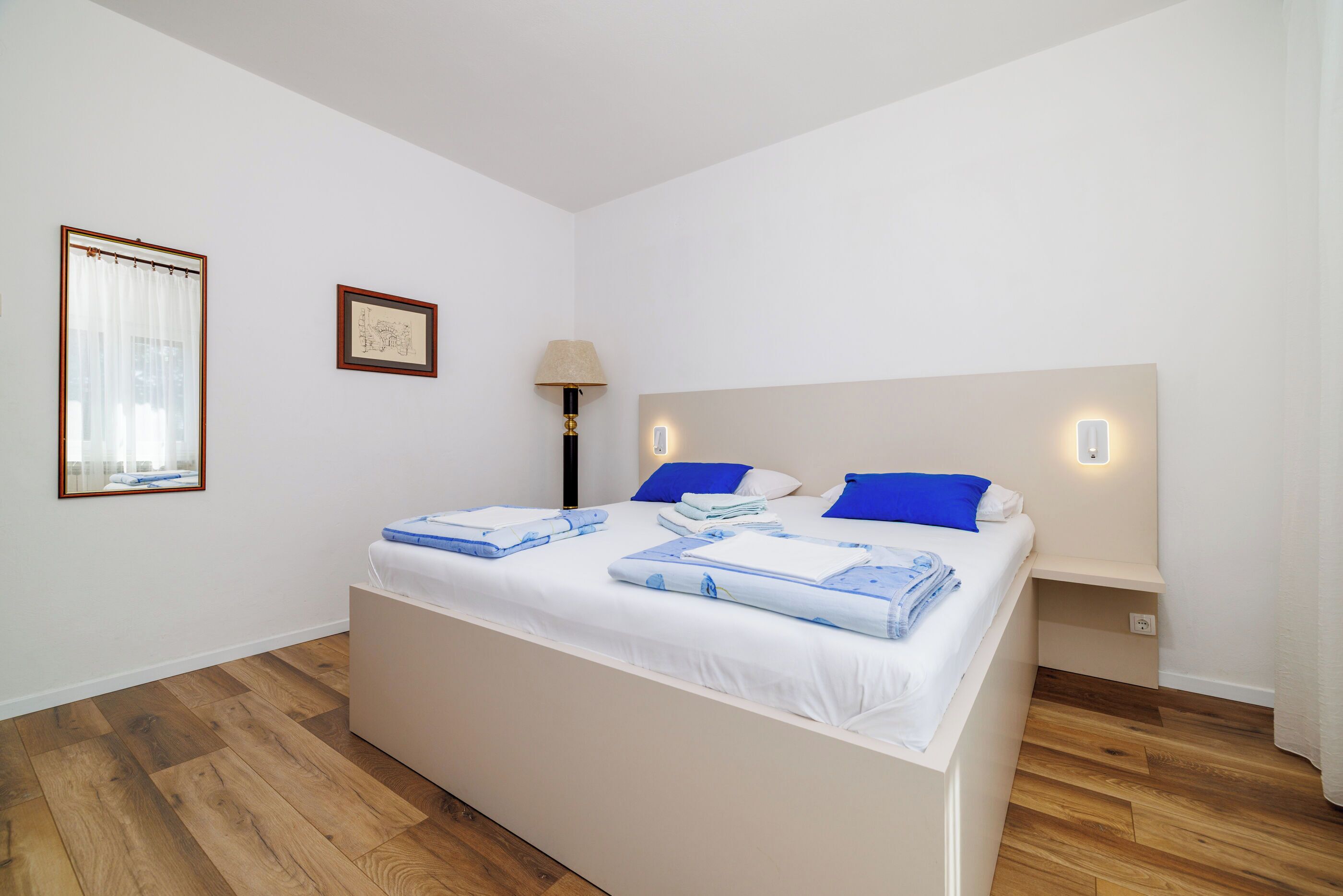 A bedroom with a bed, bedside tables, a lamp, and a framed picture on the wall.