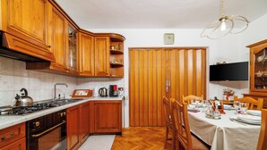 Une cuisine avec des meubles de rangement en bois, une cuisinière et une table à manger pour quatre personnes.