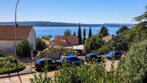 Une ville côtière où les voitures sont garées, avec un ciel bleu dégagé et une vue sur la mer.