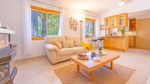 Ein Wohnzimmer mit Sofa, Couchtisch und Küchenzeile mit Schränken und Arbeitsplatte.