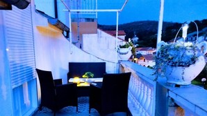 Un balcon avec une table et des chaises, un pot de fleurs et une rambarde.
