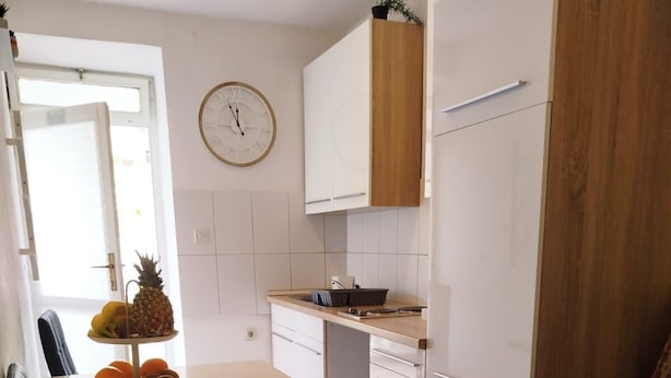 Une cuisine compacte avec un coin repas, une horloge au mur et un petit coin salon.