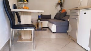 Un espace de vie compact comprenant une table à manger, un canapé, une chaise et un coin cuisine.