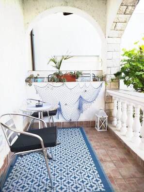 A small outdoor seating area with a table and chairs, a patterned rug, and potted plants. - Apartments Rose (Sibenik)