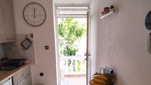 Une cuisine avec une table à manger, une horloge et une vue sur la verdure à l’extérieur.