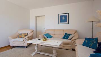 A living room with a beige sofa, a white coffee table, and a beige armchair.