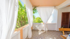 A balcony with white curtains, a wooden bench, and a table. - Apartments Rasic (Rab)