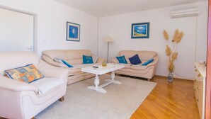 A living room with two beige sofas, a white coffee table, and a vase with pampas grass. - Apartments Rasic (Rab)