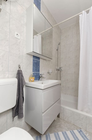 A bathroom with a white sink, mirror, and shower. - Apartment Rose Garden (Rovinj)