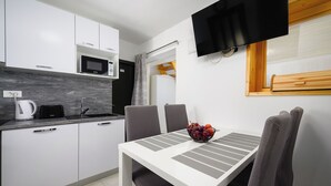A modern kitchen with white cabinets, a microwave, and a dining area with a table and chairs. - House Miha (Tar-Vabriga)