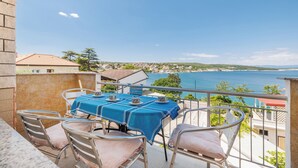 Ein Balkon mit einem Tisch für vier Personen, mit Blick auf die Küste.
