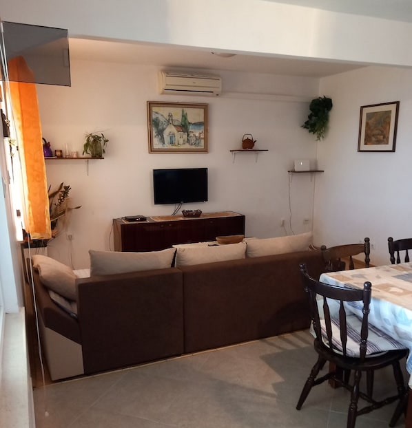 A living room with a sofa, a TV, a dining table with chairs, and artwork on the walls. - House Garma (Blato)