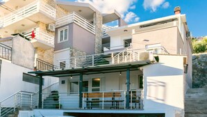 A multi-story building with balconies, staircases, and a covered outdoor seating area. - Apartment Golubinka (Dugi Rat)