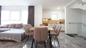 A modern living room with a dining area, a kitchen, and a staircase. - Apartment Tin (Sveti Filip i Jakov)