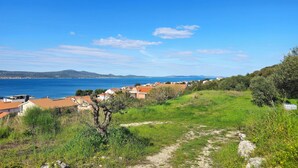 A coastal village with terracotta-roofed houses, a clear blue sea, and a hilly landscape in the background. - Apartment Tin (Sveti Filip i Jakov)