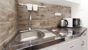 A modern kitchen with a stainless steel sink, a microwave, and a kettle on the counter. - Apartments Darinka (Vodice)