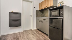 A compact kitchen with a built-in microwave, a stainless steel refrigerator, wooden cabinets, and a small potted plant. - Apartments Darinka (Vodice)