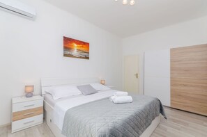 Une chambre à coucher moderne avec un lit, des tables de chevet, un tableau et une armoire.