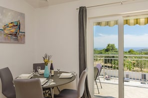 Un comedor con una mesa dispuesta para dos, un florero con flores y un cuadro en la pared.
