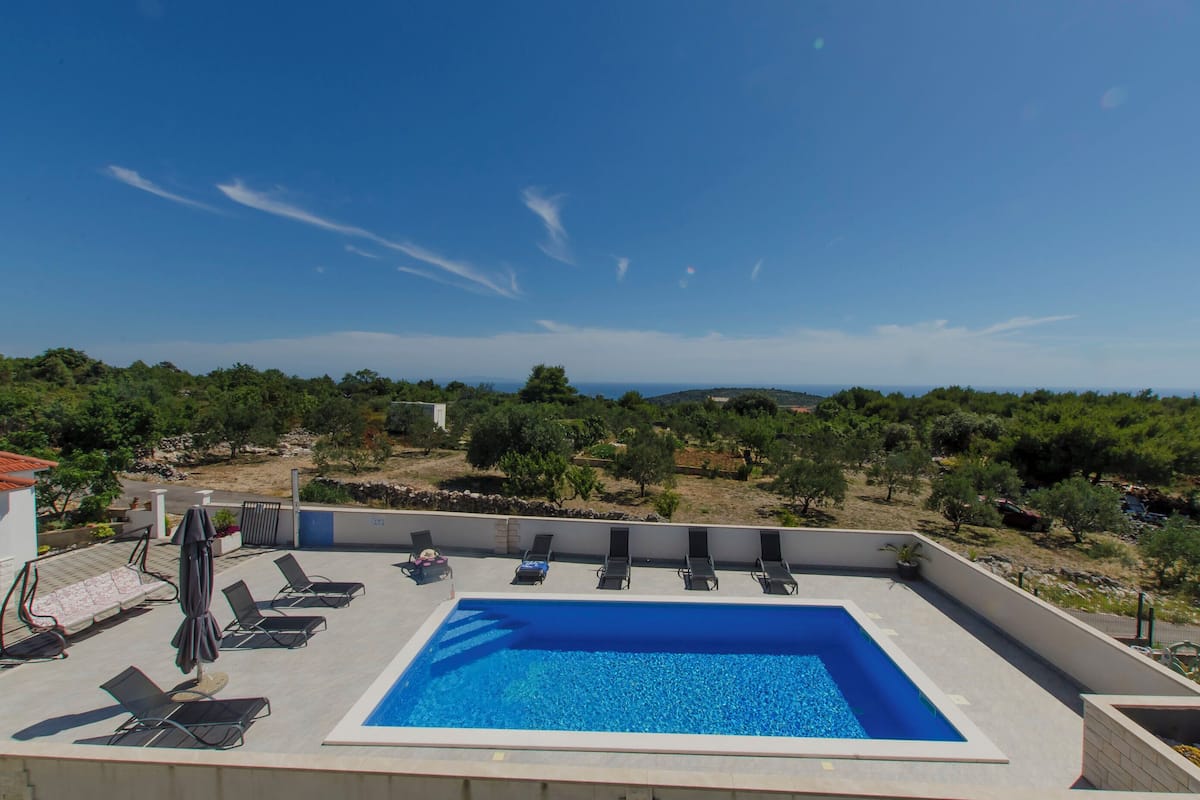 Una piscina en la azotea con sillones de descanso y vistas del paisaje circundante.