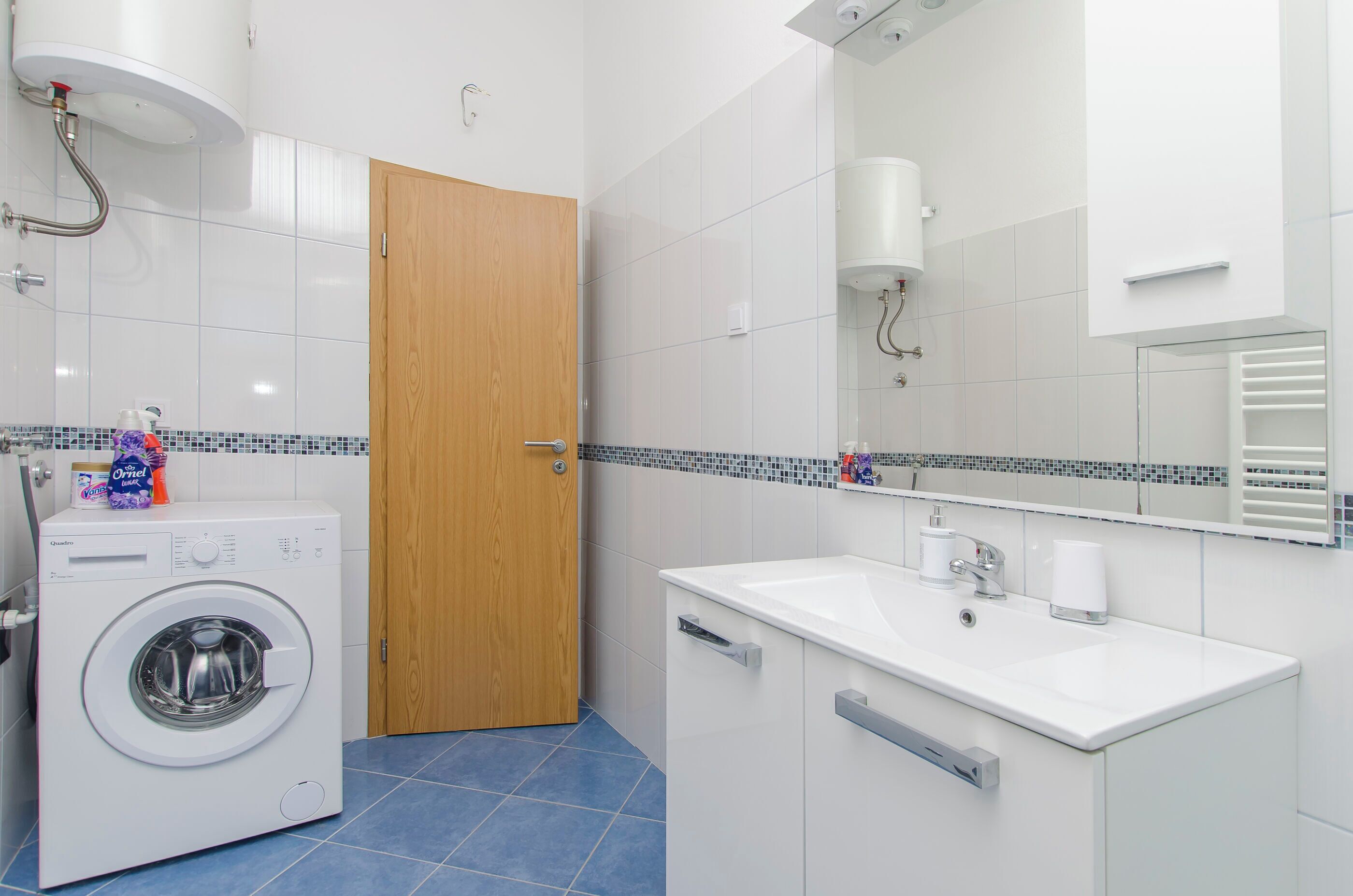 Un bagno moderno con lavatrice, lavandino e specchio.