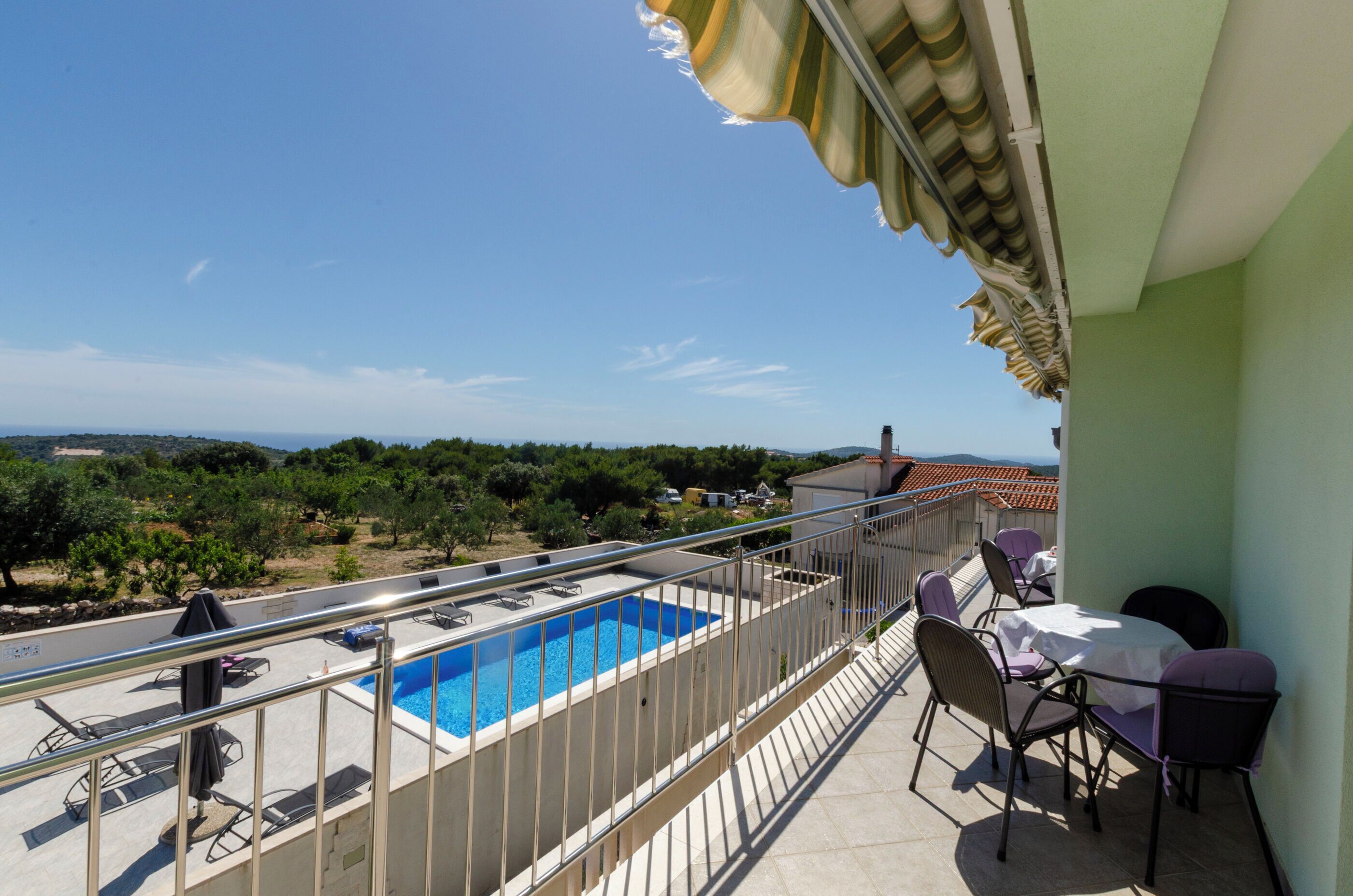 Un balcone con piscina, sedie e un tavolo.