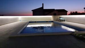 A swimming pool with a lounge chair and a house in the background. - Apartments Marija (Rogoznica)