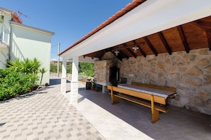 Un espacio de estar al aire libre cubierto con un muro de piedra, un banco de madera y un patio con baldosas.