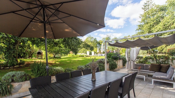 An outdoor patio with a dining table, chairs, and a large umbrella. - House Cetiri Hrasta (Pican)